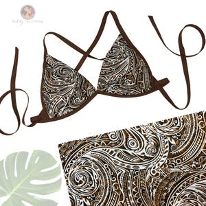 May include: A brown and white patterned bikini top with matching bottoms. The bikini top has triangle cups and thin straps. The fabric features a detailed tribal design in brown and white. The image includes a leaf and the text "Made By Tara O'Polife".
