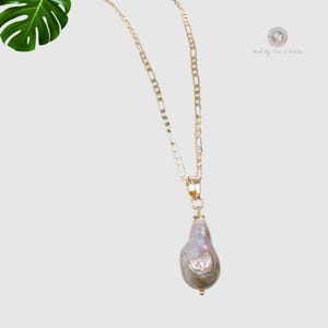 May include: A gold chain necklace with a large, pearlescent, baroque pearl pendant.