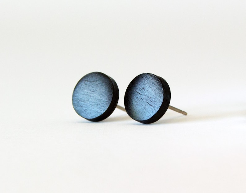 May include: A pair of round wooden earrings with a black and blue gradient finish.