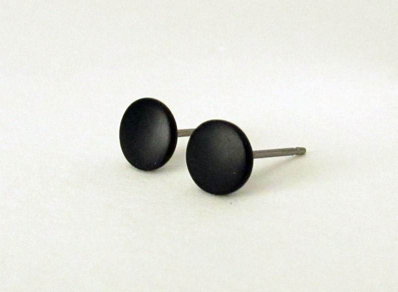 Op de afbeelding: Een paar zwarte oorbel studs met zilveren pinnen.
