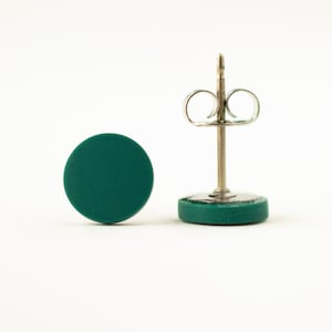 May include: A pair of teal green round stud earrings with silver posts and butterfly backs.