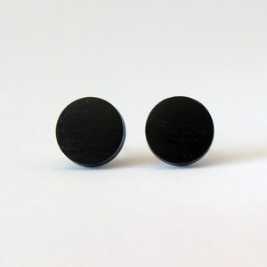 May include: A pair of black wooden circle stud earrings.