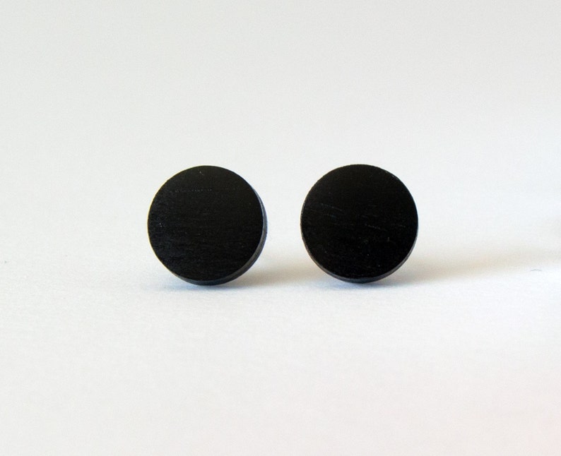 May include: A pair of black wooden circle stud earrings.