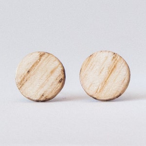 May include: A pair of round wooden earrings with a light brown wood grain pattern.