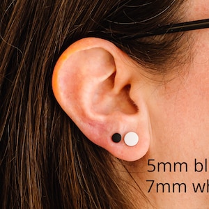 Op de afbeelding: Een oor met twee oorringen, een zwarte en een witte. De zwarte oorring is 5 mm en de witte oorring is 7 mm.