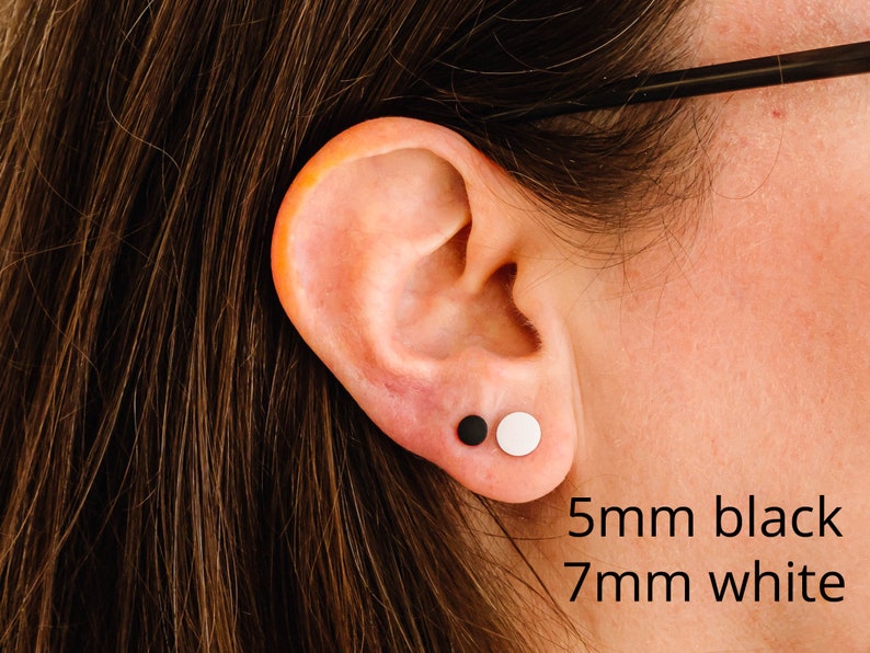 Op de afbeelding: Een oor met twee oorringen, een zwarte en een witte. De zwarte oorring is 5 mm en de witte oorring is 7 mm.