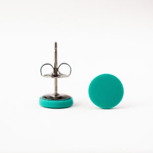 Op de afbeelding: Een paar tealblauwe oorbel studs met zilveren pinnen en vlinder achterkanten.
