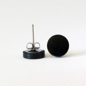 May include: A pair of black wood stud earrings with silver posts.