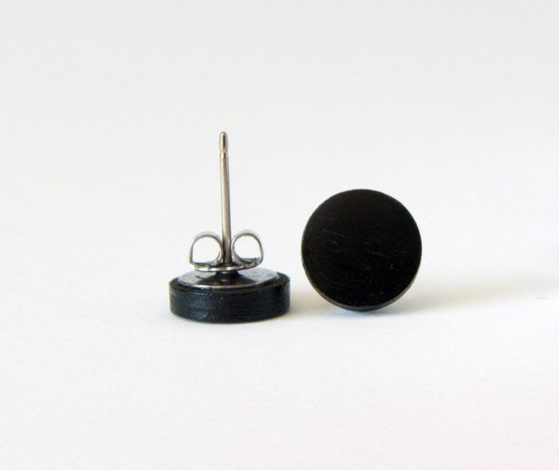 May include: A pair of black wood stud earrings with silver posts.
