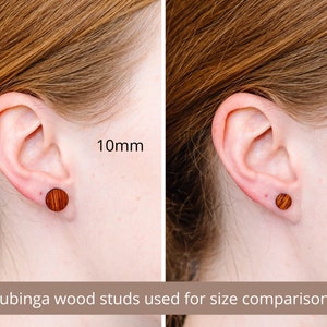 May include: Two wooden earrings in different sizes, 10mm and 7mm, shown in a person's ear for size comparison. The earrings are made of bubinga wood.