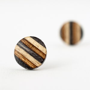 May include: A pair of round wooden earrings with a striped pattern in black, brown, and white.