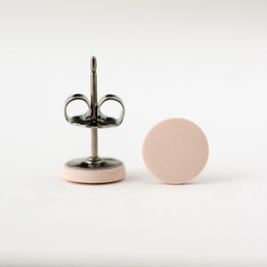 May include: A pair of pink round stud earrings with silver posts and backs.