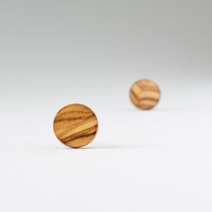 May include: Two round wooden earrings with a natural wood grain pattern.