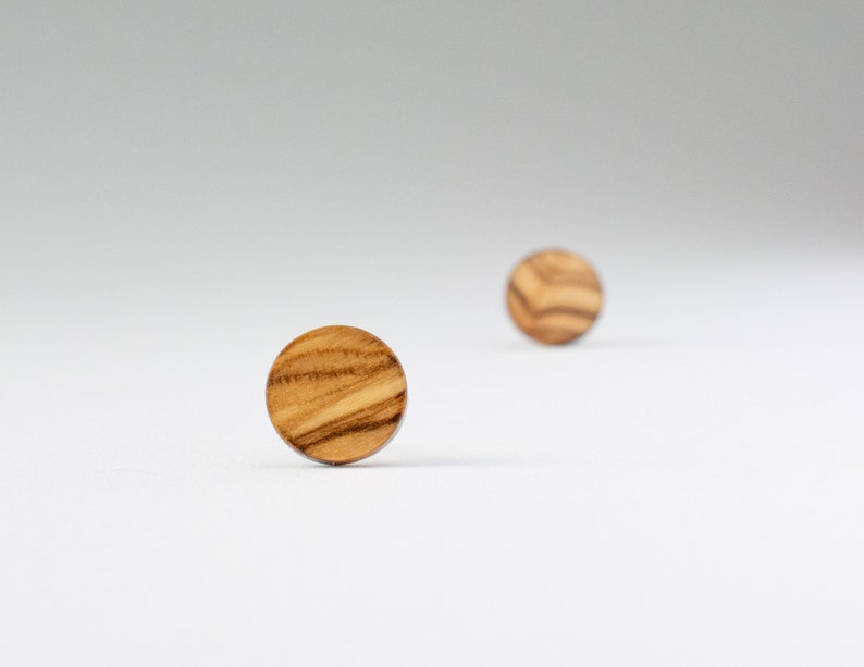 May include: Two round wooden earrings with a natural wood grain pattern.
