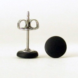 Op de afbeelding: Een paar zwarte oorbel studs met een zilveren pin en vlinder achterkant.