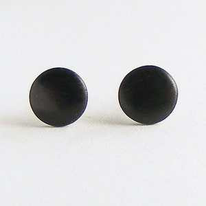 Op de afbeelding: Een paar zwarte ronde oorbel studs. De oorbellen zijn klein en eenvoudig, met een gladde, matte afwerking.