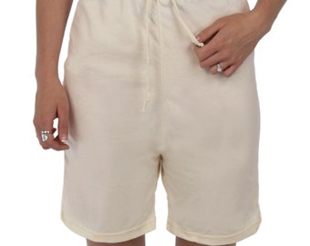 May include: Off-white shorts featuring an elasticized waistband with a matching drawstring tie. The shorts are constructed from a plain, light-colored fabric and reach mid-thigh, providing a simple and functional design for casual wear.