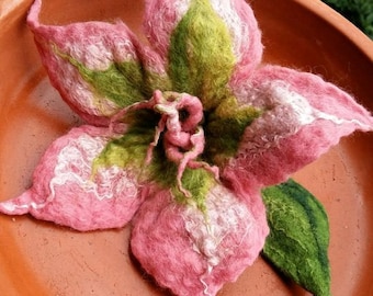 May include: A handcrafted felt flower in shades of pink, green, and white, resting in a terracotta-colored bowl. The flower has detailed petals and a textured appearance, showcasing a unique, artistic design. The bowl is approximately 10 inches in diameter.
