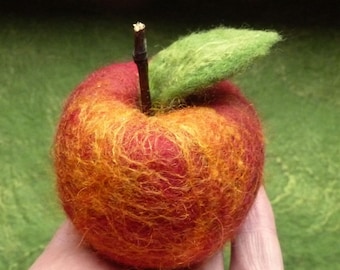 May include: A hand-felted apple with a red and orange color gradient. The apple has a green felt leaf attached to the top.