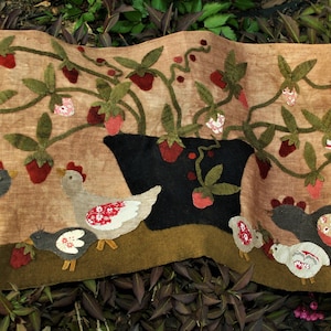 May include: A brown fabric wall hanging with a green vine and red strawberries. The vine is growing out of a black pot. There are five gray and white chickens at the bottom of the hanging.