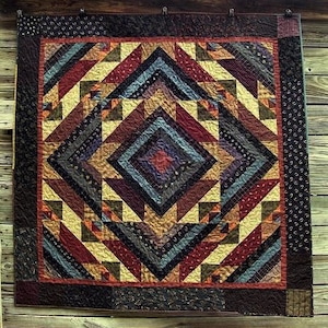 Puede incluir: Una colcha con un patrón geométrico en tonos de marrón, rojo, amarillo y azul. La colcha está hecha de cuadrados y triángulos, y el patrón se repite en toda la colcha.