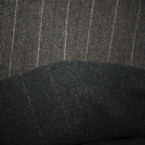 May include: A close-up of a brown and black striped fabric with a black fabric lining. The fabric has a subtle texture.
