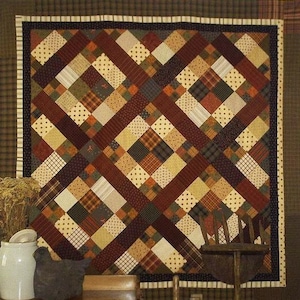 Pode incluir: Uma colcha com um design de patchwork que apresenta uma variedade de tecidos marrons, bege e verdes. A colcha é feita de quadrados e diamantes, e os padrões dos tecidos incluem xadrez, bolinhas e estampas florais.
