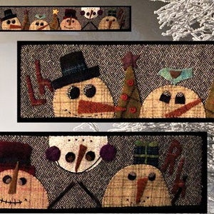 May include: A close-up of a handmade felt Christmas decoration featuring a row of snowmen with various hats and accessories. The snowmen are arranged on a brown fabric background with a herringbone pattern.