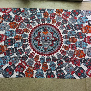 May include: White tapestry with a circular design of colorful sugar skulls and a mandala pattern. The tapestry is surrounded by a border of smaller sugar skulls.