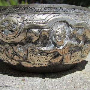 May include: A silver bowl with intricate embossed designs featuring a human figure and floral patterns.