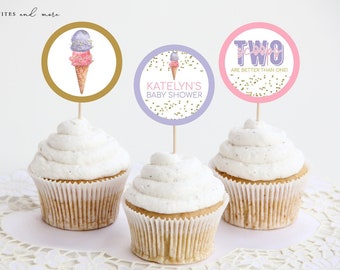 May include: Three cupcakes with white frosting and gold glitter sprinkles. Each cupcake has a round, colorful paper topper with an ice cream cone design and text. The toppers say "Katelyn's Baby Shower", "Two Scoops Are Better Than One!" and "Ice Cream".