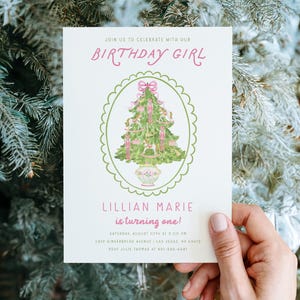 May include: A white rectangular birthday invitation card featuring a green scalloped oval frame containing a watercolor illustration of a Christmas tree decorated with pink ribbons and ornaments in a floral pot, with text reading BIRTHDAY GIRL.