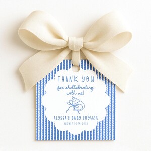 May include: A square gift tag with a scalloped white center featuring blue text that reads THANK YOU for shellebrating with us! ALYSSA'S BABY SHOWER AUGUST 10TH 20XX and a blue seashell icon. The tag has blue vertical stripes and a cream ribbon bow.