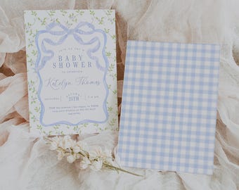 May include: A blue and white baby shower invitation with a blue bow and floral accents. The invitation reads "Join us for a Baby Shower to celebrate Katelyn Thomas Saturday, August 25th, 2:00 pm 8768 Two Avenue | Las Vegas, NV 89248 RSVP Julie Thomas | 745-057-8419 Registry"