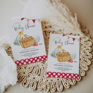 May include: Two red and white gingham patterned baby shower invitations with a watercolor illustration of a picnic basket, flowers, and strawberries. The text on the invitations reads "Join us for a Baby Shower" and "To celebrate Mom-to-be Stephanie Johnson".