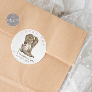 May include: Round white thank you sticker with a brown cowboy boot with pink flowers and the text "Thank You" in pink. The text "Alyssa's Baby Shower" and "October 21, 20XX" is also on the sticker.