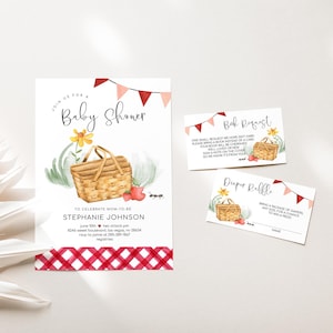 May include: A printable baby shower invitation with a red and white gingham pattern at the bottom. The invitation features a watercolor illustration of a picnic basket with flowers, strawberries, and ants. The text on the invitation reads "Join us for a Baby Shower" and includes the name "Stephanie Johnson" and the date and time of the shower. The invitation also includes a request for guests to bring a book instead of a card and a diaper raffle.
