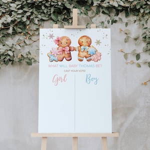 May include: A gender reveal party sign with two gingerbread people, one in pink and one in blue, with the text "What will baby Thomas be? Cast your vote! Girl Boy"