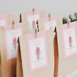 May include: Brown paper bags with pink and white gingham patterned labels. The labels have a watercolor illustration of an ice cream cone with a pink scoop and a blue ribbon. The text on the labels reads "Thank You" and "For celebrating with me".