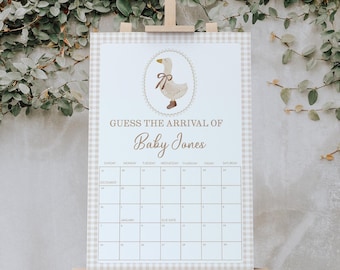 May include: A baby shower calendar with a beige and white gingham border. The calendar features a goose illustration and the text "Guess the Arrival of Baby Jones." It is displayed on a wooden easel.