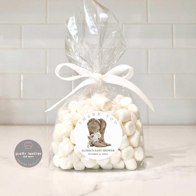 May include: A white favor bag filled with white marshmallows and a round thank you sticker with a brown cowboy boot illustration and pink flowers. The sticker says "Thank You" and "Alyssa's Baby Shower October 21, 20XX".