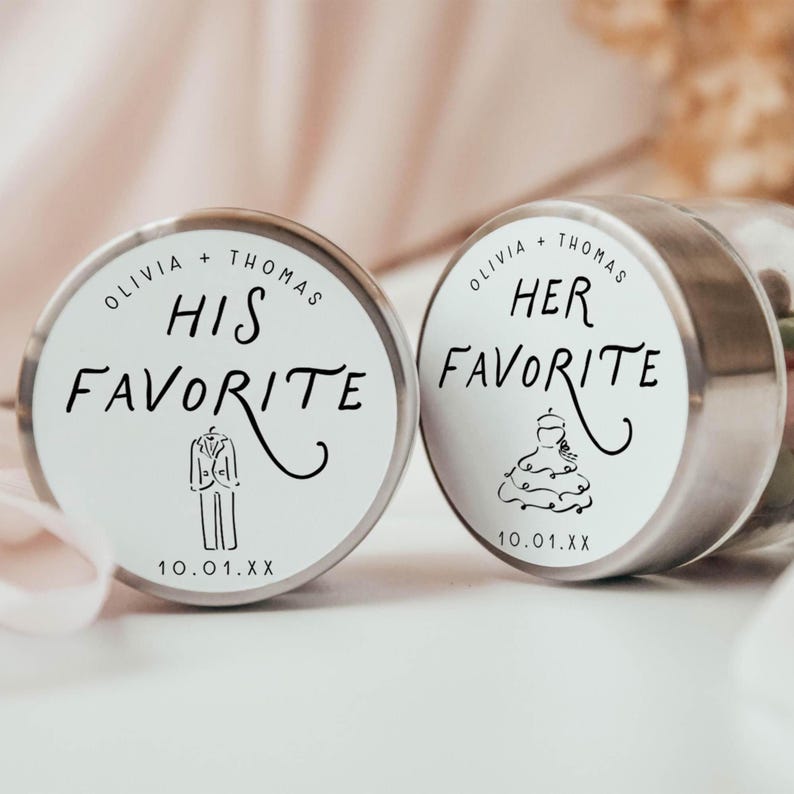 May include: Two small, round, silver-lidded containers with white labels. One reads "Olivia + Thomas HIS FAVORITE" with a tuxedo illustration. The other says "Olivia + Thomas HER FAVORITE" with a wedding dress illustration. Both have a date.