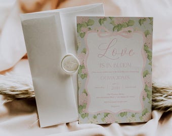 May include: A floral-themed bridal shower invitation with a pink and green color scheme. The invitation features a delicate floral border and the text "Love is in Bloom" with the bride's name, Olivia Jones, and the date of the shower. The invitation is accompanied by a white envelope with a wax seal.