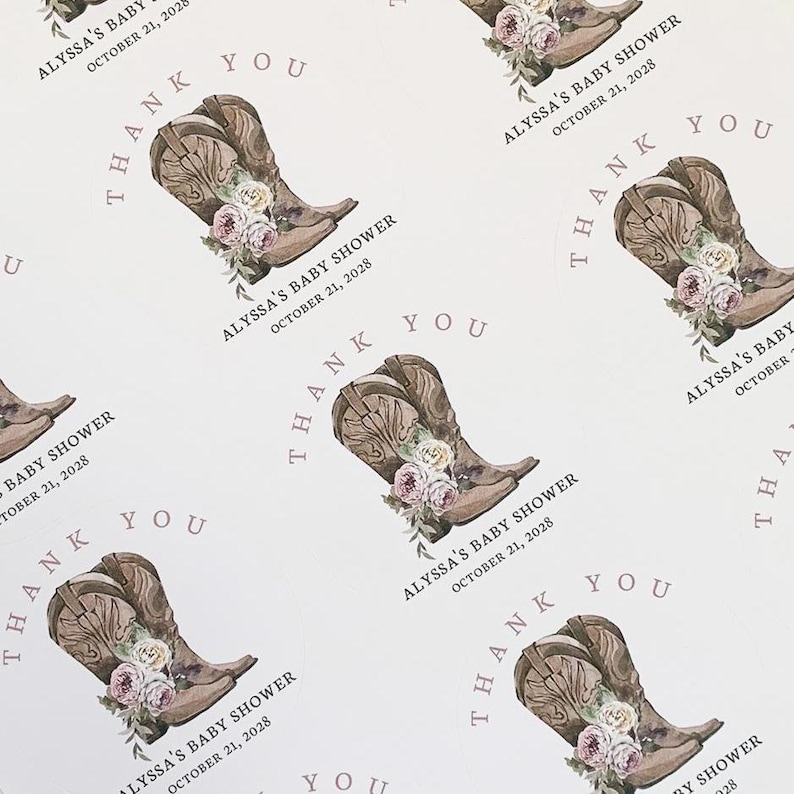 May include: Thank you favor tags with a watercolor illustration of brown cowboy boots with pink and white flowers. The text on the tag reads "Alyssa's Baby Shower October 21, 2028 Thank You".