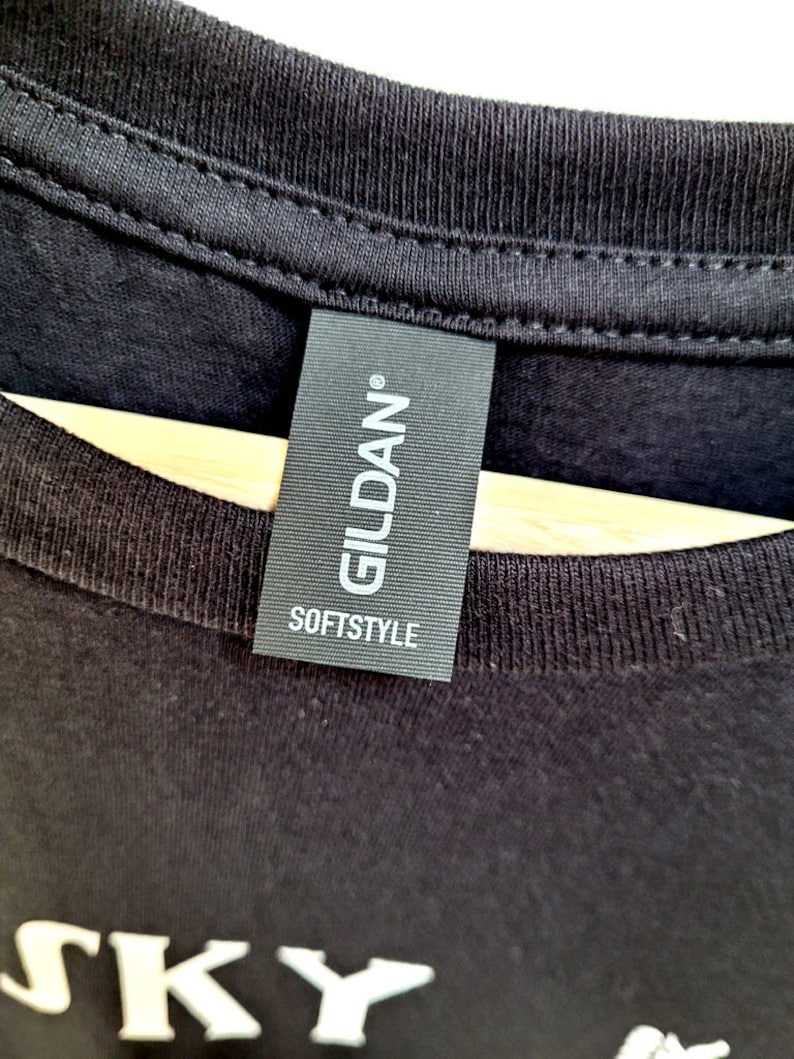 May include: A black Gildan Softstyle t-shirt with the word "SKY" printed in white on the front.