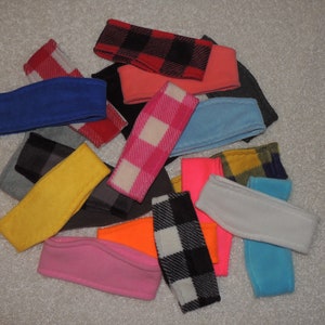 May include: A collection of colorful fleece headbands in various patterns, including plaid, checkered, and solid colors. The headbands are made of soft, comfortable fleece and are perfect for keeping your ears warm in the winter.