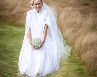 A quirky waterproof bridal cloak to protect a bride and her wedding dress from rain, puddles and mud. Arrive pristine whatever the weather.