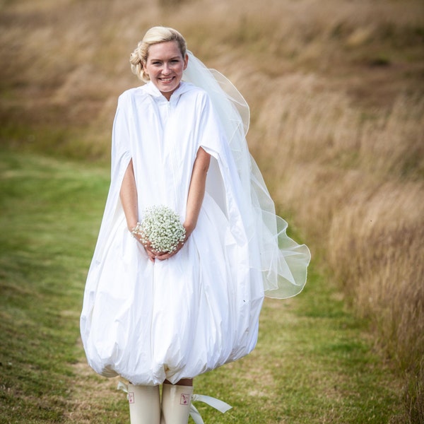 Ein schrulliger wasserfester Brautmantel, um eine Braut und ihr Brautkleid vor Regen, Pfützen und Schlamm zu schützen. Kommen Sie tadellos an, egal bei welchem Wetter.