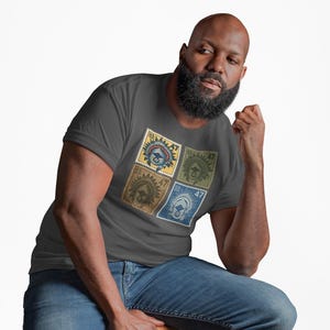 May include: Dark gray t-shirt featuring four postage stamp designs with a military theme. The stamps are in yellow, green, brown, and blue, each with a US 47 cent value. The shirt is paired with blue jeans.