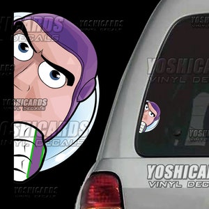 May include: A vinyl decal featuring a cartoon image of Buzz Lightyear from Toy Story. The decal shows Buzz's face peeking out from behind a black background. The text "YOSHICARDS VINYL DECALS" is printed on the decal.